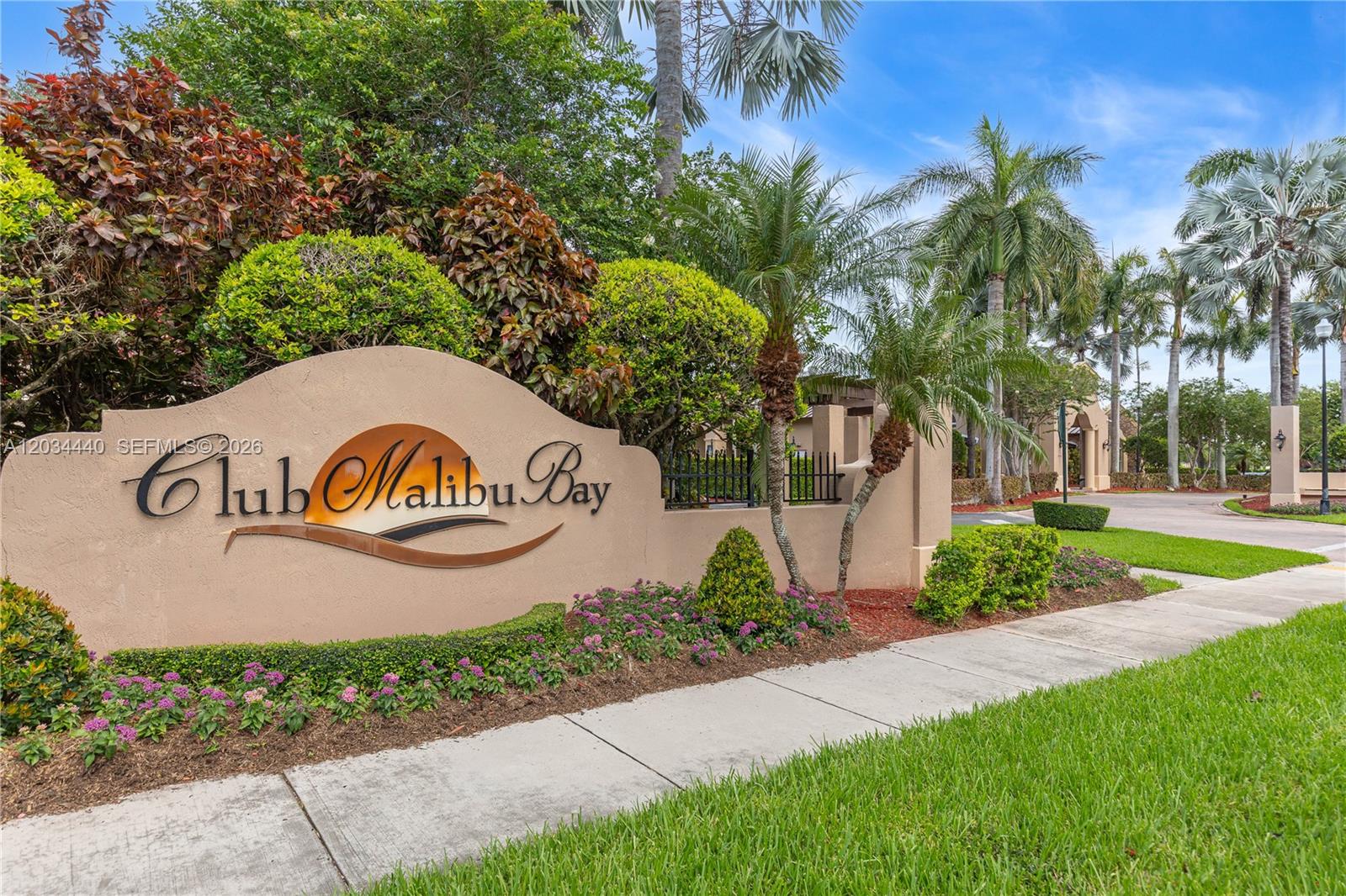A beige stucco sign for Club Malibu Bay sits in a landscaped residential entrance area — 1490 NE 33rd Rd # 18, Homestead FL 33033, HOMESTEAD, FL