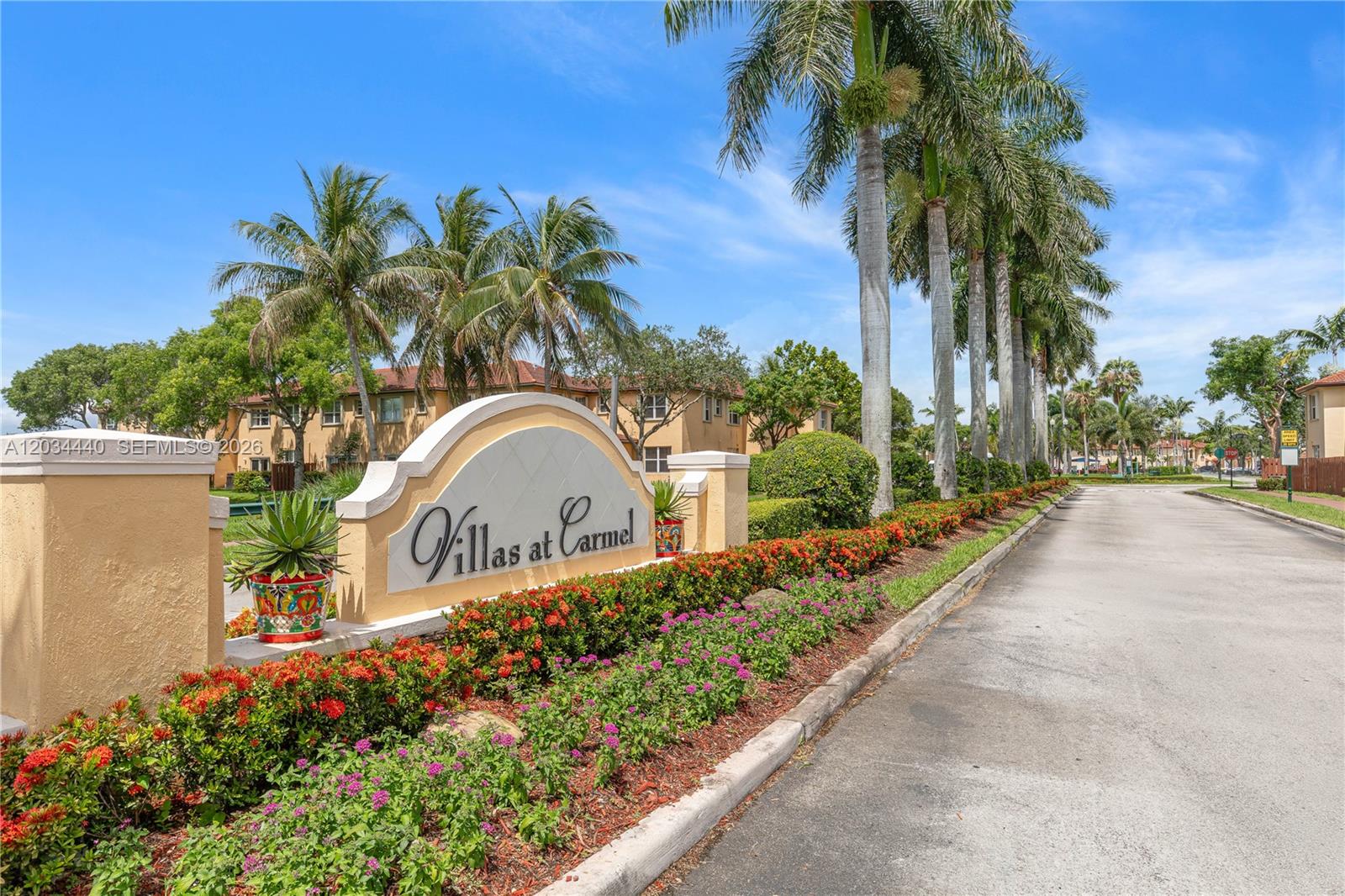 The entrance sign for Villas at Carmel features palm trees and colorful landscaping — 1490 NE 33rd Rd # 18, Homestead FL 33033, HOMESTEAD, FL