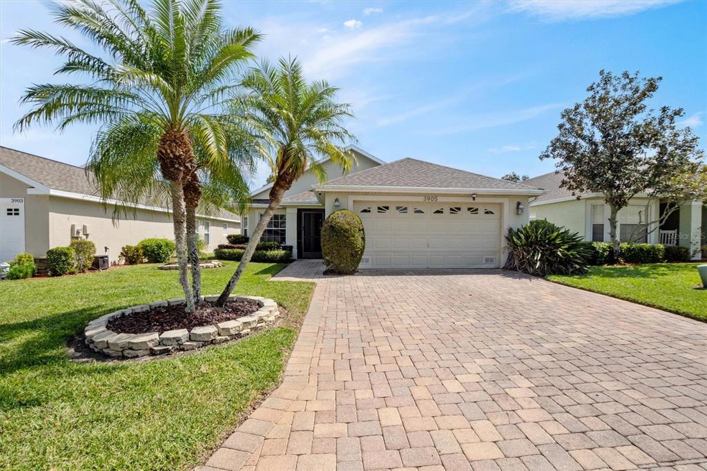 A single-story house with a paved driveway, a palm tree, and a two-car garage — 3905 OSPREY POINTE CIRCLE, WINTER HAVEN, FL