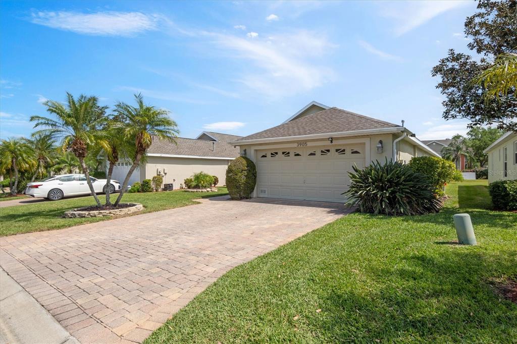 A single-story house with a beige exterior, a two-car garage, and a paved driveway — 3905 OSPREY POINTE CIRCLE, WINTER HAVEN, FL
