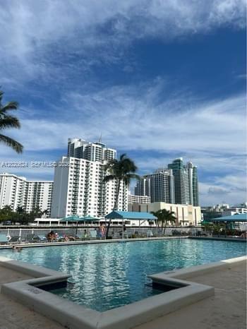 A swimming pool overlooks a waterfront view of high-rise buildings under a blue sky — 800 Parkview Dr # 406, Hallandale Beach FL 33009, HALLANDALE BEACH, FL