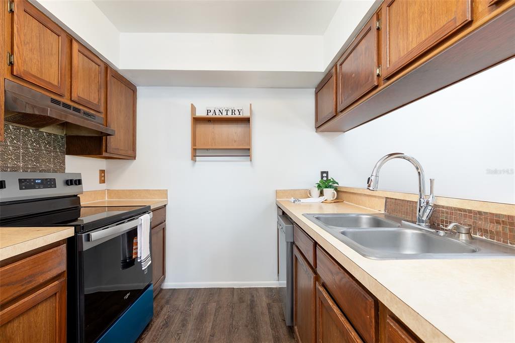 A galley kitchen features wood cabinets, laminate countertops, a stainless steel sink, and a stove — 2745 TALLY HO AVENUE, ORLANDO, FL
