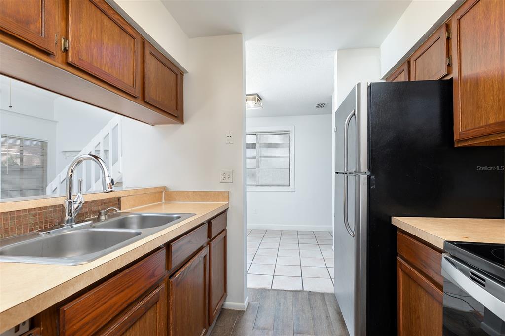 A kitchen features wood cabinets, laminate countertops, a stainless steel sink, and a black refrigerator — 2745 TALLY HO AVENUE, ORLANDO, FL