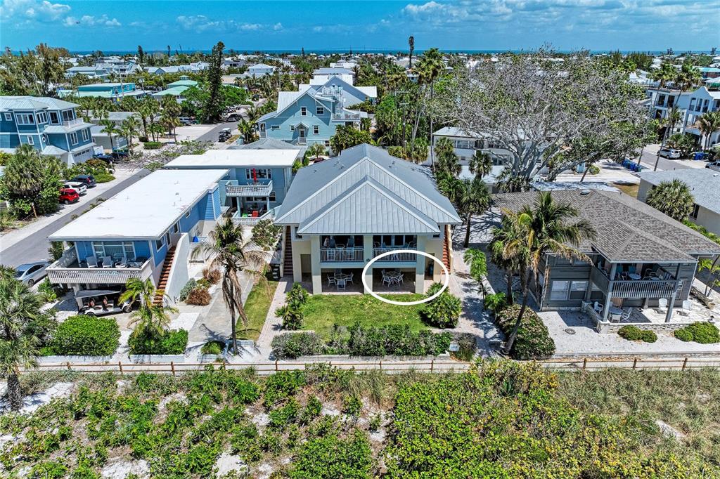 An aerial view shows a multi-story house with a ground-level patio and balcony — 101 PALM AVENUE UNIT 1, ANNA MARIA, FL