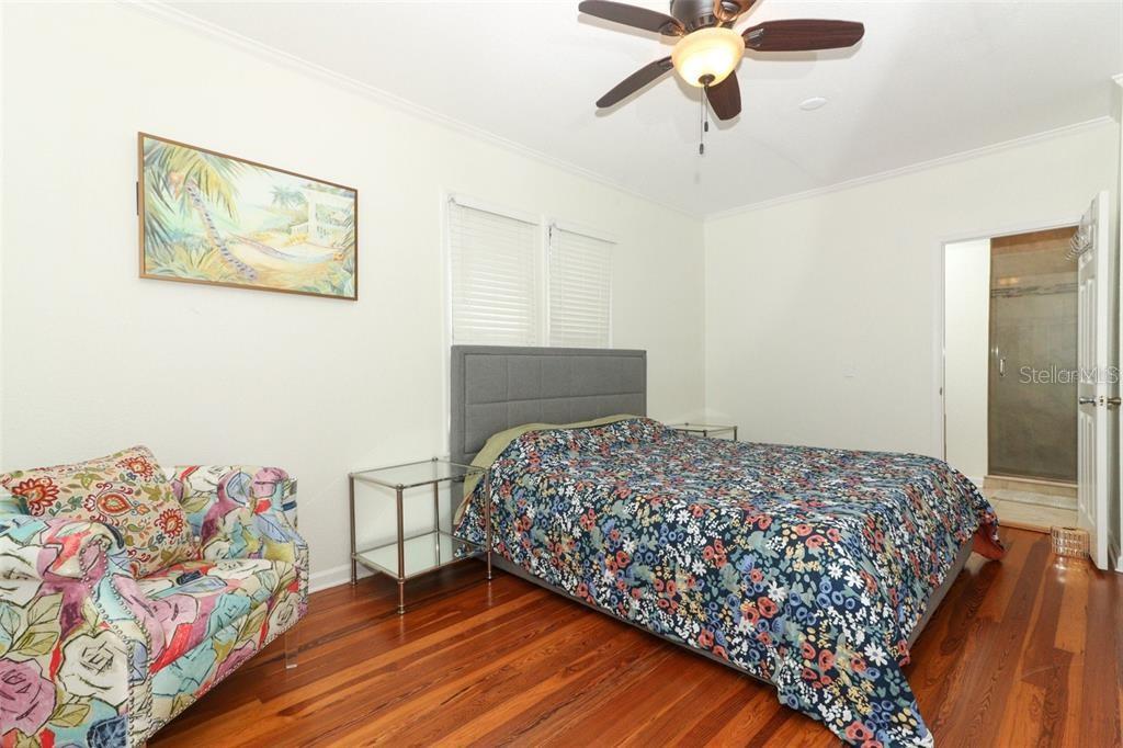 A bedroom features a bed with a floral quilt, a patterned armchair, and hardwood floors — 1442 PALM AVENUE, WINTER PARK, FL
