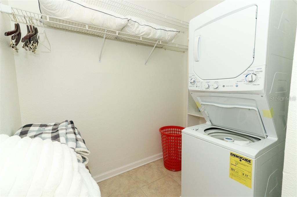 A laundry room features a stacked washer and dryer, a wire shelf, and a red basket — 1442 PALM AVENUE, WINTER PARK, FL