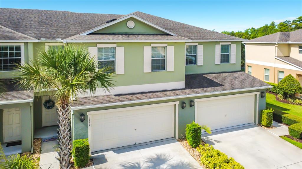 An exterior view of a two-story townhouse with light green siding and two garage doors — 3554 RODRICK CIRCLE, ORLANDO, FL