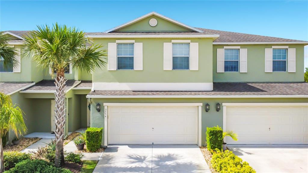 A two-story townhouse with a light green exterior, white shutters, and two attached garages — 3554 RODRICK CIRCLE, ORLANDO, FL