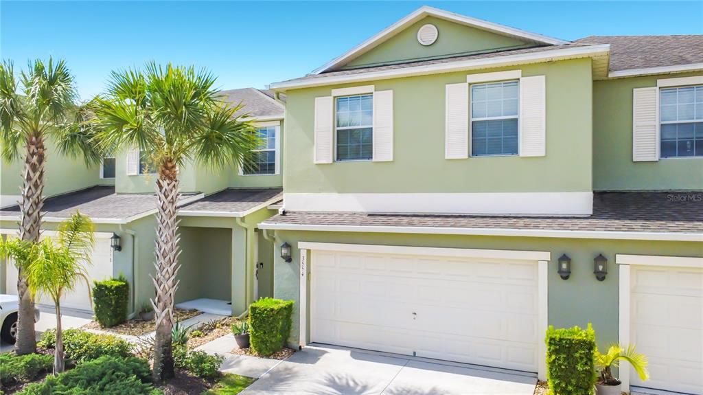 An exterior view of a two-story light green townhouse with a white garage door — 3554 RODRICK CIRCLE, ORLANDO, FL