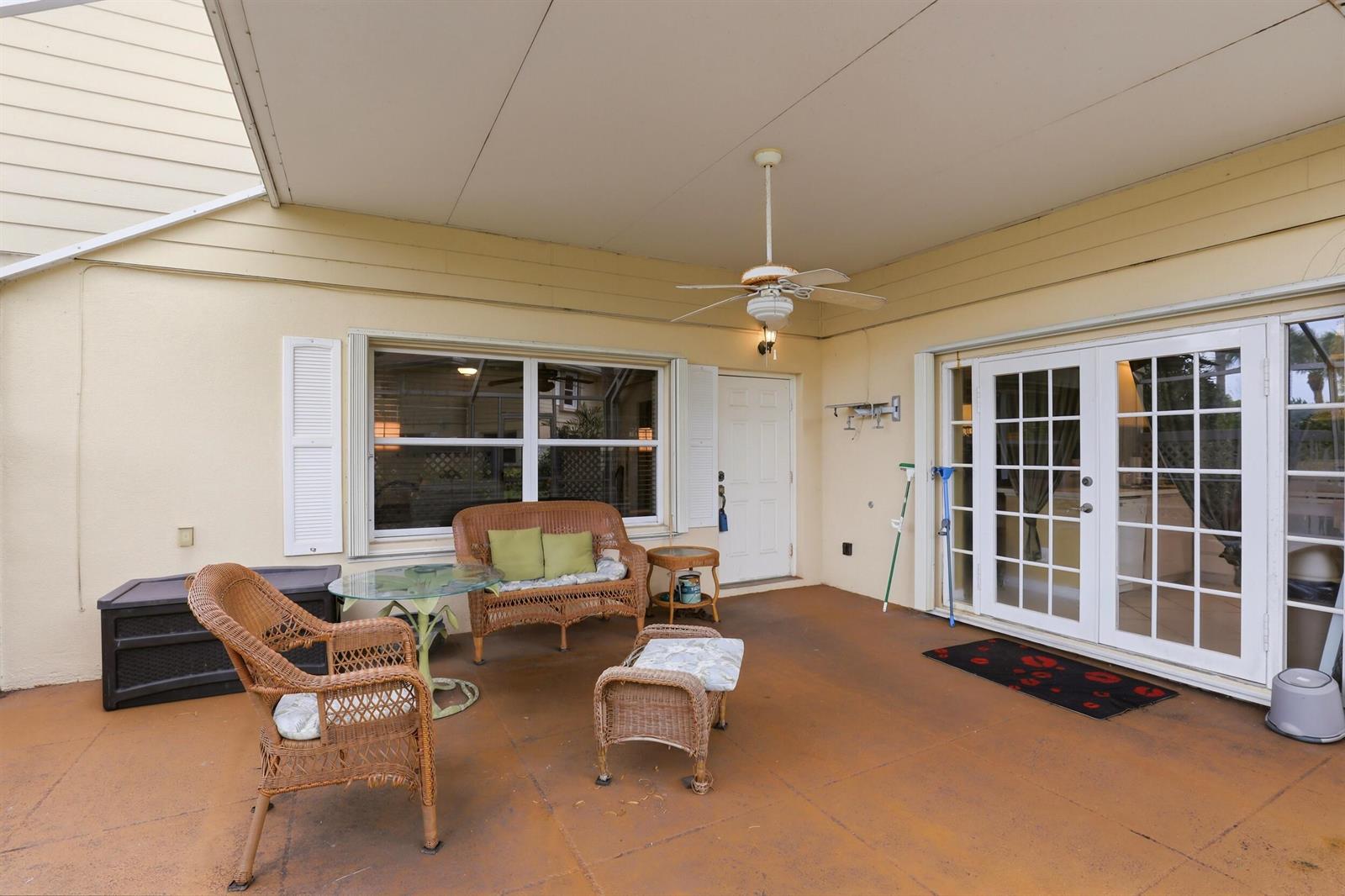 A covered patio features wicker furniture, a ceiling fan, and French doors leading inside — 6604 Dryden Court # D, Boynton Beach FL 33436, BOYNTON BEACH, FL