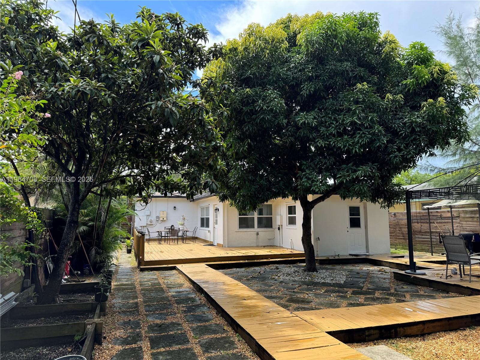 A grassy backyard features a wooden fence, several outdoor chairs, and a two-story building — 2247 Jackson St, Hollywood FL 33020, HOLLYWOOD, FL
