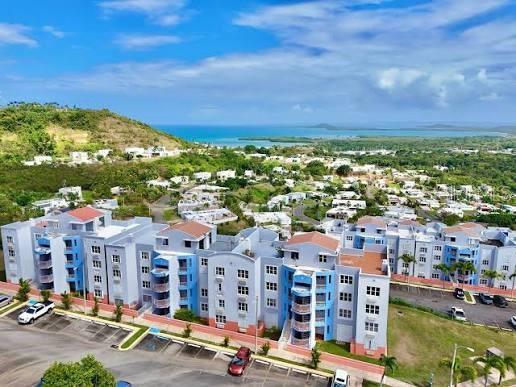 An aerial view of a multi-story apartment complex with blue accents near a coastal hillside — PH-7 LA COSTA APTS UNIT H-7, FAJARDO, PR