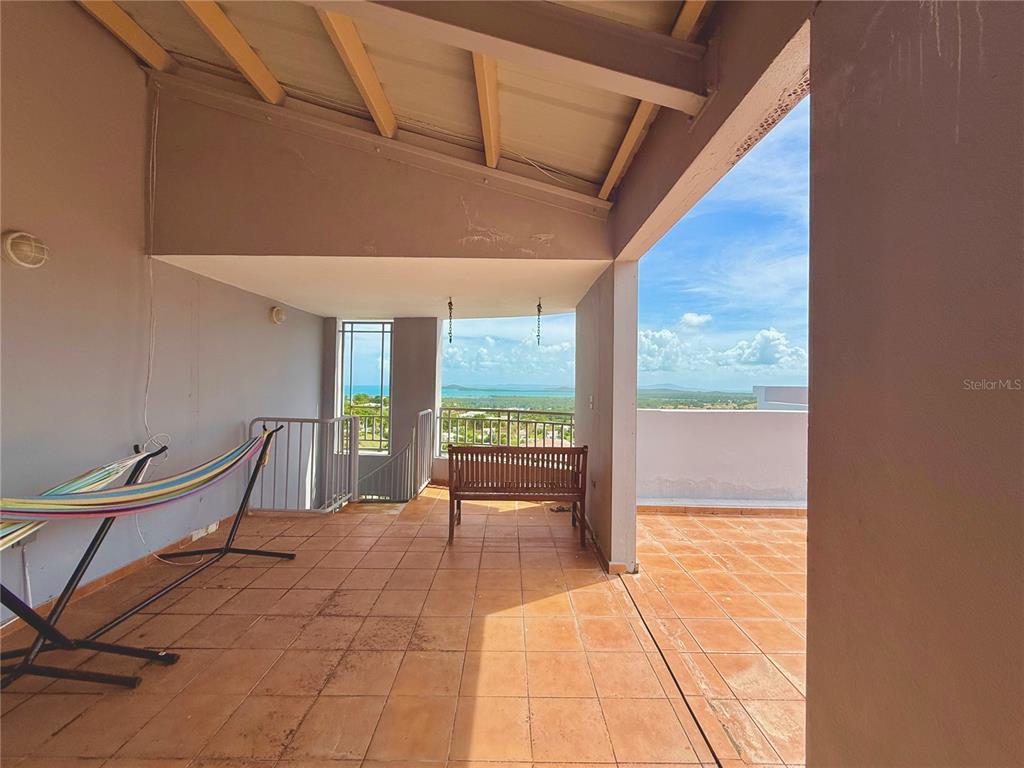 A covered outdoor patio features terracotta tile flooring, a hammock, and a wooden bench — PH-7 LA COSTA APTS UNIT H-7, FAJARDO, PR