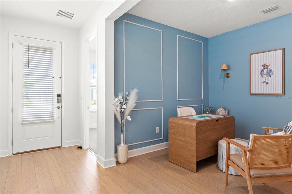 A home office features blue paneled walls, a wooden desk, and a cane-back chair — 16186 HONEY HARVEST STREET, WINTER GARDEN, FL