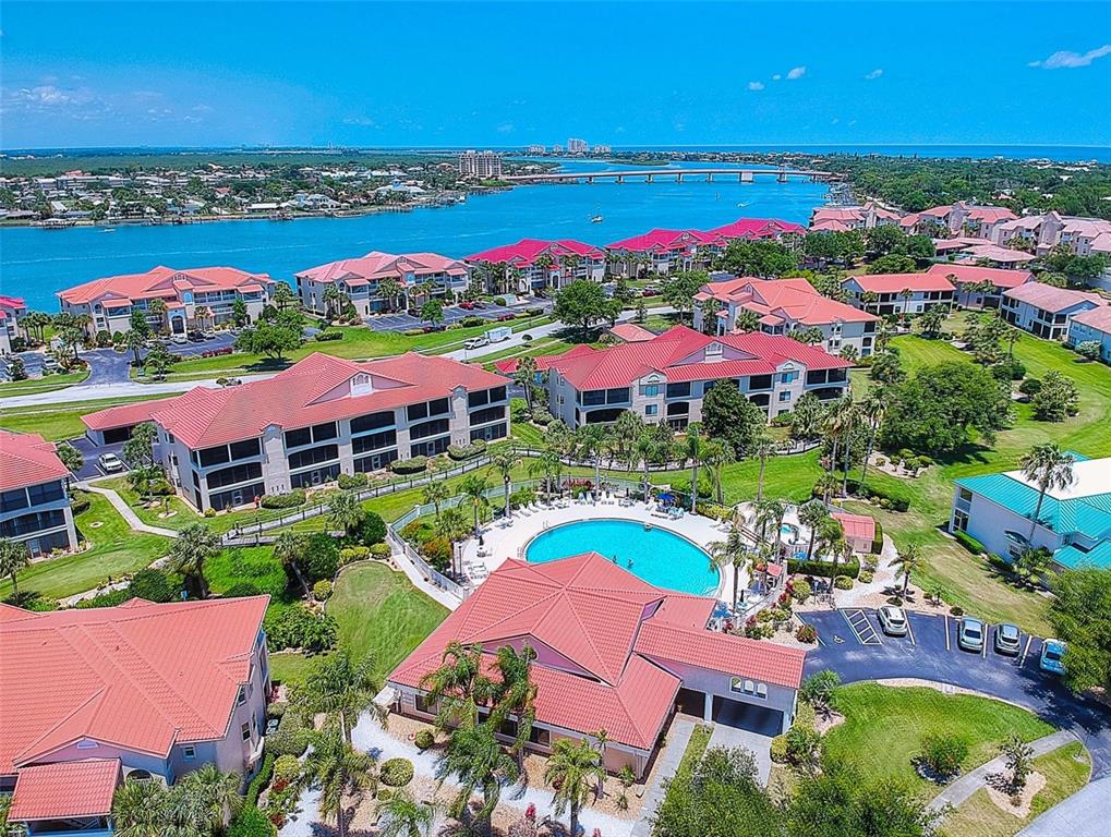 An aerial view shows a residential complex with red-tiled roofs and a central swimming pool — 444 BOUCHELLE DRIVE UNIT 201, NEW SMYRNA BEACH, FL