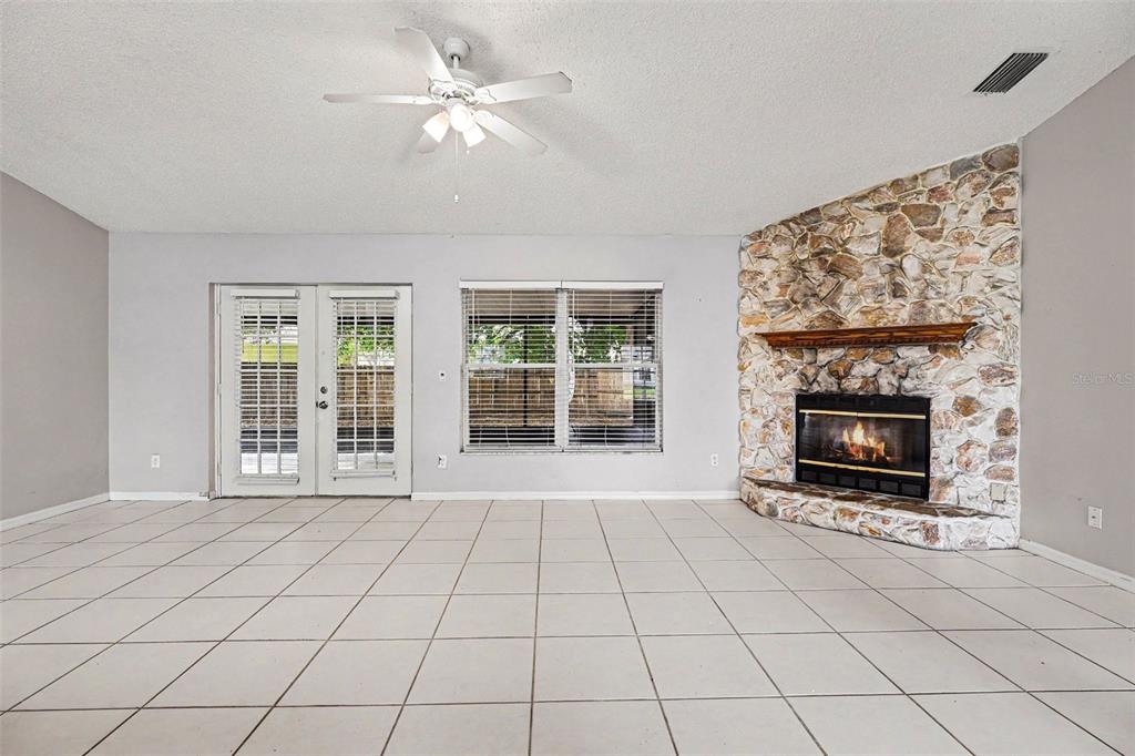 A living room features white tile flooring, a stone fireplace, and glass patio doors — 805 TOPAZ DRIVE, ROCKLEDGE, FL