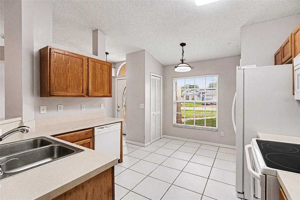 A kitchen with white tile floors, wood cabinets, white appliances, and a window overlooking a street — 805 TOPAZ DRIVE, ROCKLEDGE, FL