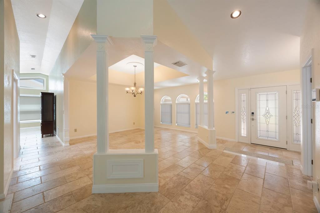 An entryway with tile flooring leads to a dining area defined by white decorative columns — 14115 HARBORWOOD DRIVE, LARGO, FL