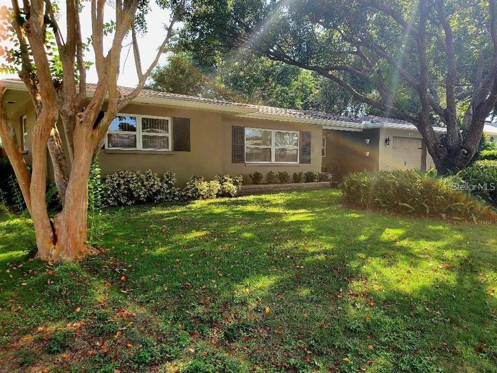 A single-story house with a tan exterior, a garage, and large trees in the yard — 1637 WHITEWOOD DRIVE, CLEARWATER, FL