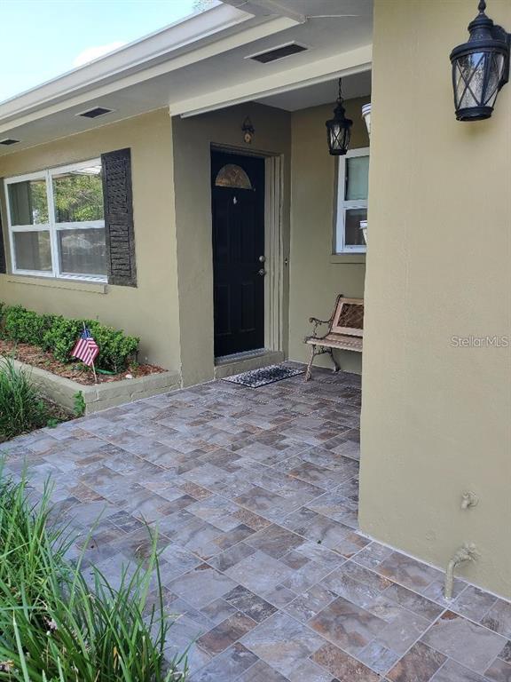 A front porch with tiled flooring, a black door, and a small bench — 1637 WHITEWOOD DRIVE, CLEARWATER, FL