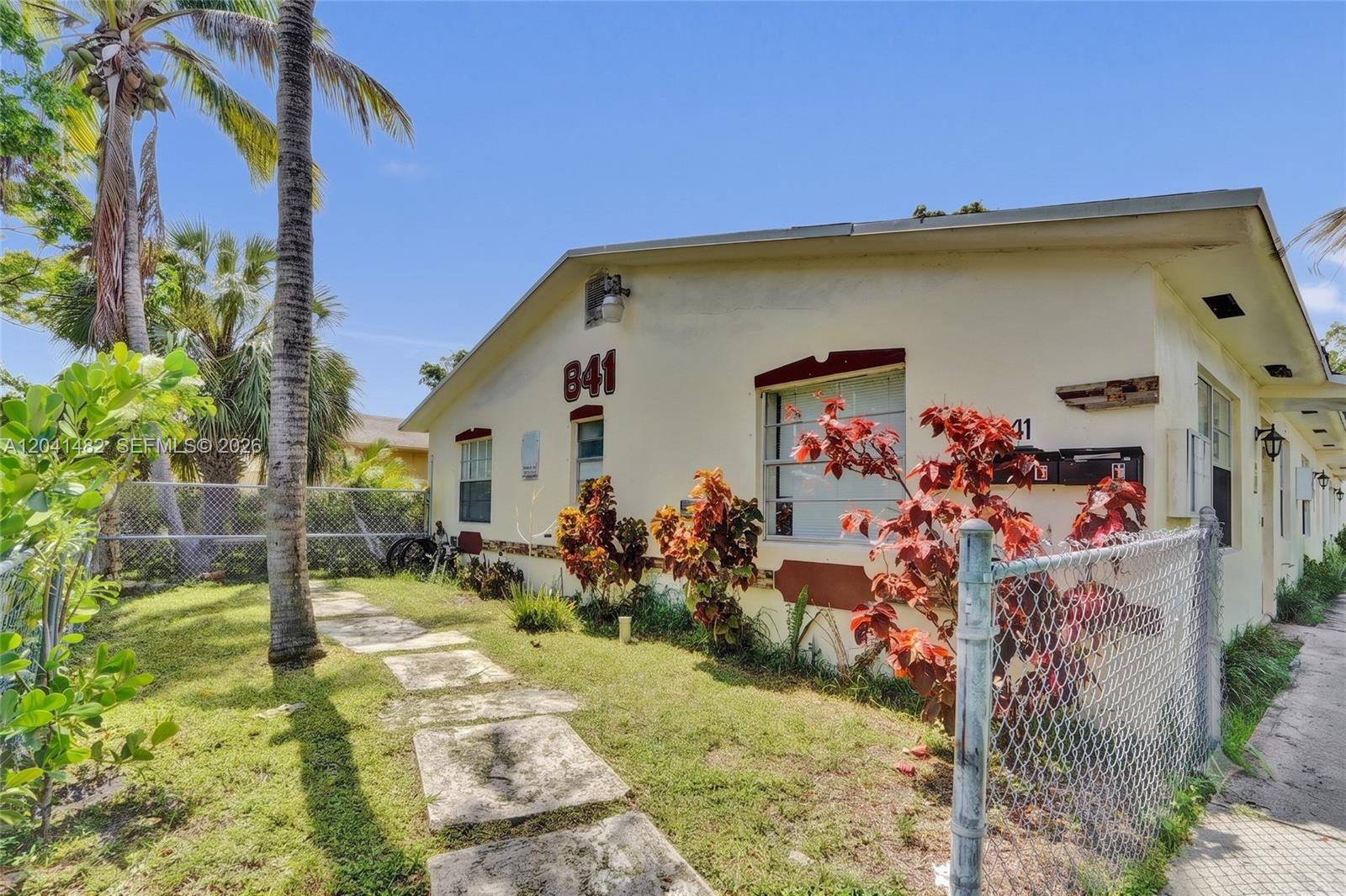 A single-story building with a cream-colored exterior, a chain-link fence, and a stone walkway — 841 SW 7th St # C, Pompano Beach FL 33060, POMPANO BEACH, FL