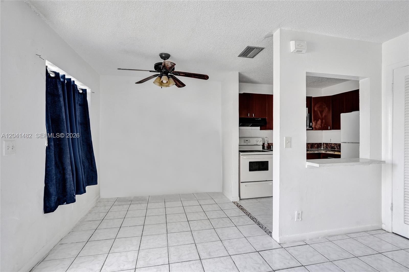 A dining area with white tile floors and a ceiling fan opens into a kitchen — 841 SW 7th St # C, Pompano Beach FL 33060, POMPANO BEACH, FL