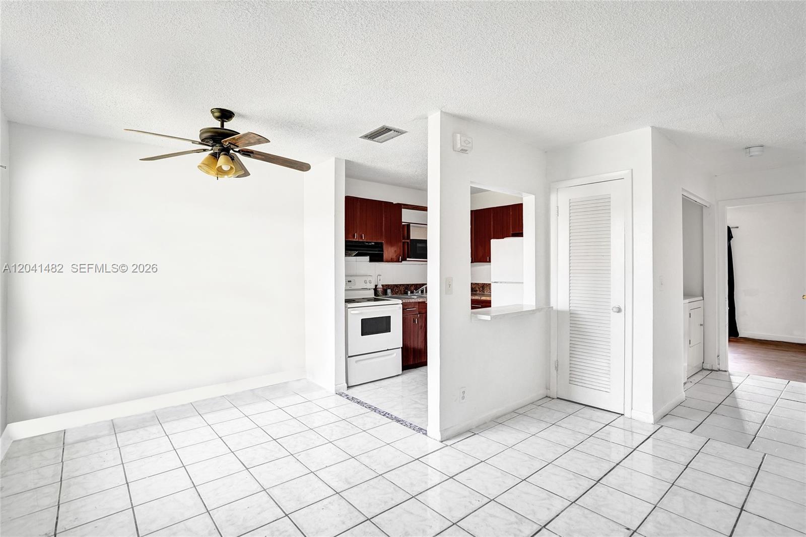 A white-tiled dining area features a ceiling fan and an open pass-through to the kitchen — 841 SW 7th St # C, Pompano Beach FL 33060, POMPANO BEACH, FL