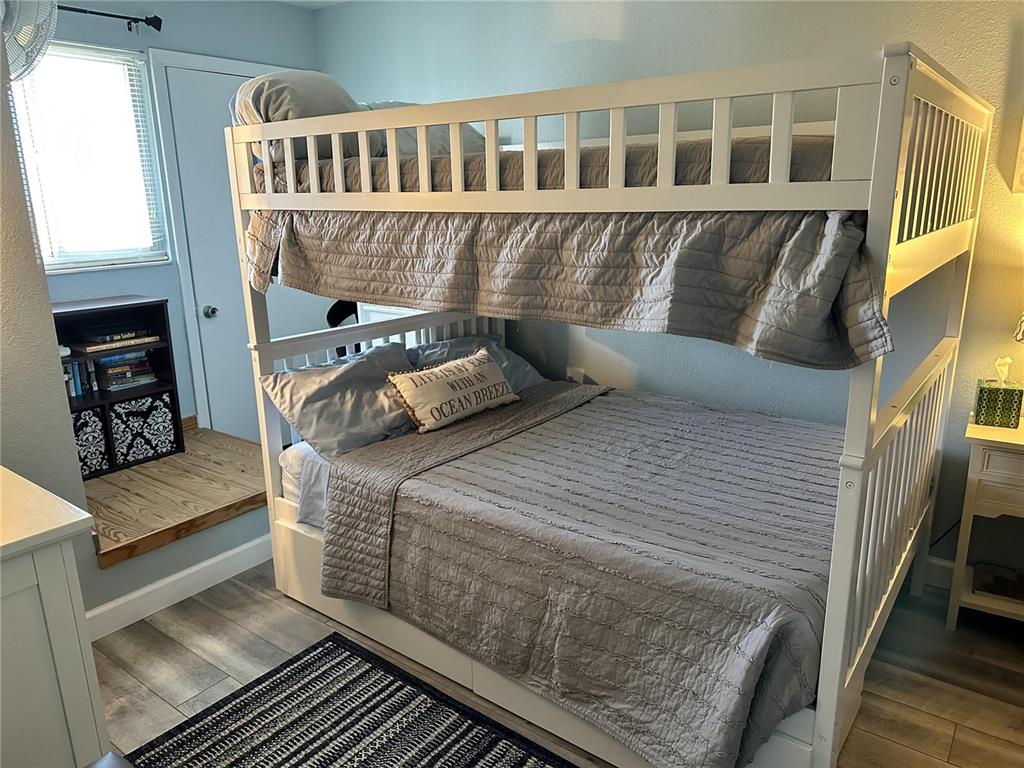A bedroom features a white wooden bunk bed with grey bedding on a wood-look floor — 4849 SAXON DRIVE UNIT A210, NEW SMYRNA BEACH, FL