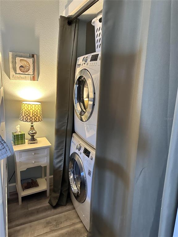 A stacked washer and dryer unit sits next to a small white side table — 4849 SAXON DRIVE UNIT A210, NEW SMYRNA BEACH, FL