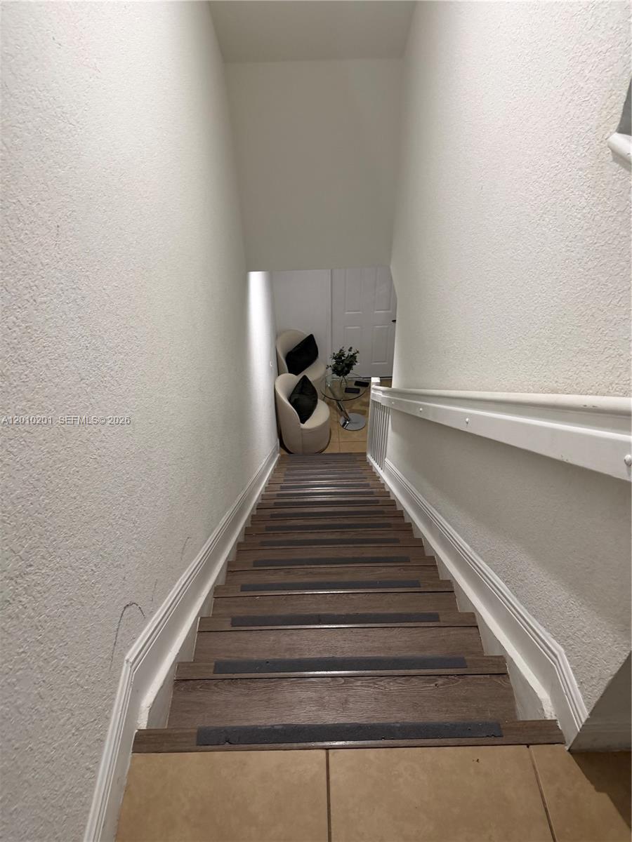 A wooden staircase with non-slip treads leads down to a small seating area — 11942 SW 26th Ct, Miramar FL 33025, MIRAMAR, FL