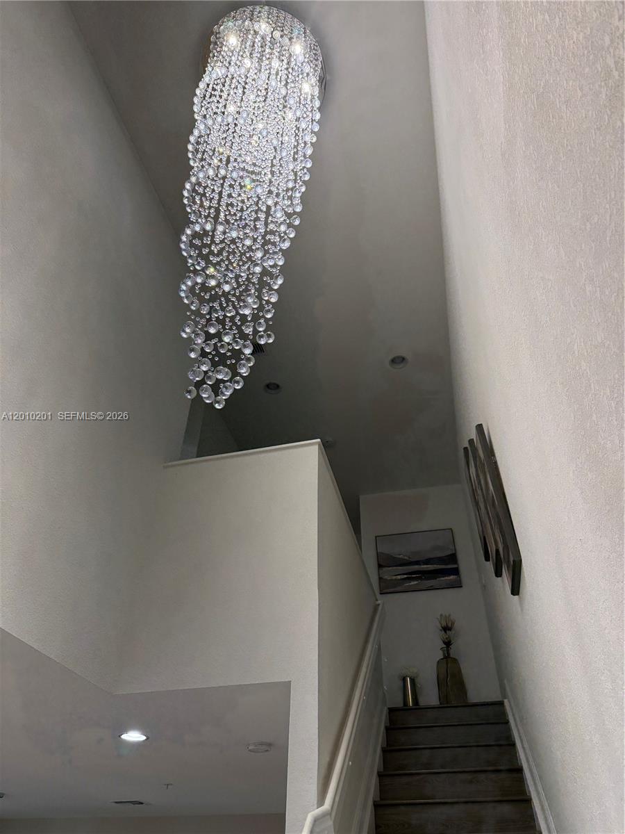 A tall staircase features a large, cascading crystal chandelier hanging from the ceiling — 11942 SW 26th Ct, Miramar FL 33025, MIRAMAR, FL