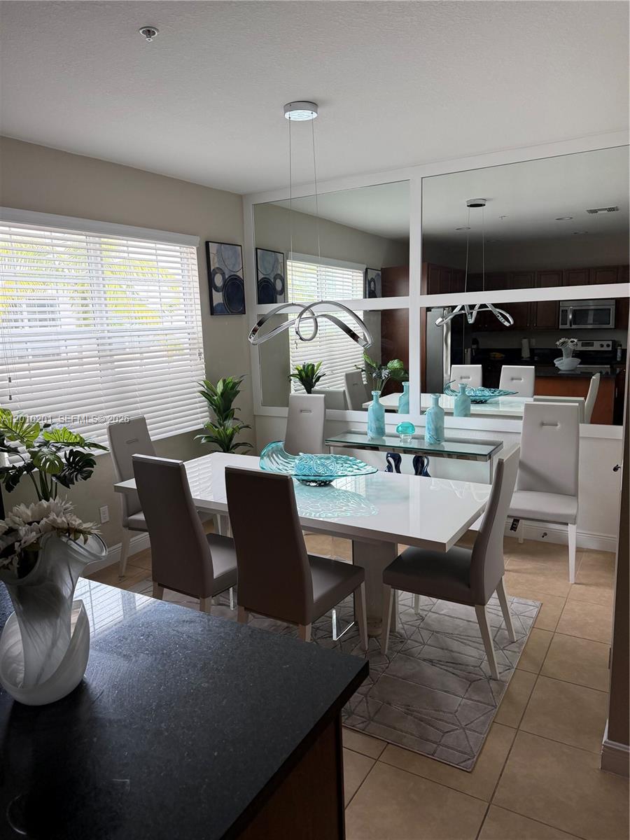 A dining room features a white table, modern chairs, a glass console, and wall mirrors — 11942 SW 26th Ct, Miramar FL 33025, MIRAMAR, FL