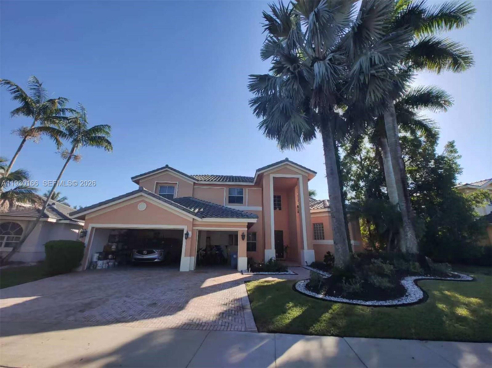 A two-story peach-colored house features a two-car garage and tall palm trees — 1035 Waterside Cir, Weston FL 33327, WESTON, FL