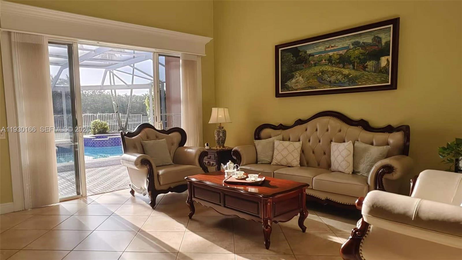 A living room features traditional furniture, a coffee table, and a view of a pool — 1035 Waterside Cir, Weston FL 33327, WESTON, FL