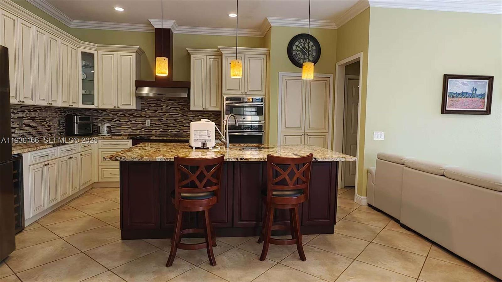 A kitchen features a granite-topped island, dark wood cabinetry, and light-colored wall cabinets — 1035 Waterside Cir, Weston FL 33327, WESTON, FL