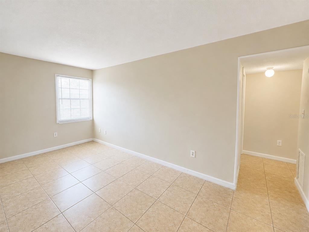 An empty room with beige walls, light-colored tile flooring, and a window with blinds — 2759 L B MCLEOD ROAD UNIT C, ORLANDO, FL