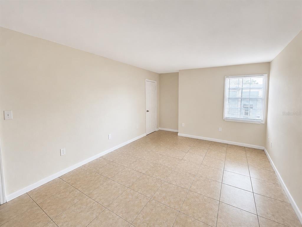 An empty room with beige walls, tan tile flooring, and a single window — 2759 L B MCLEOD ROAD UNIT C, ORLANDO, FL