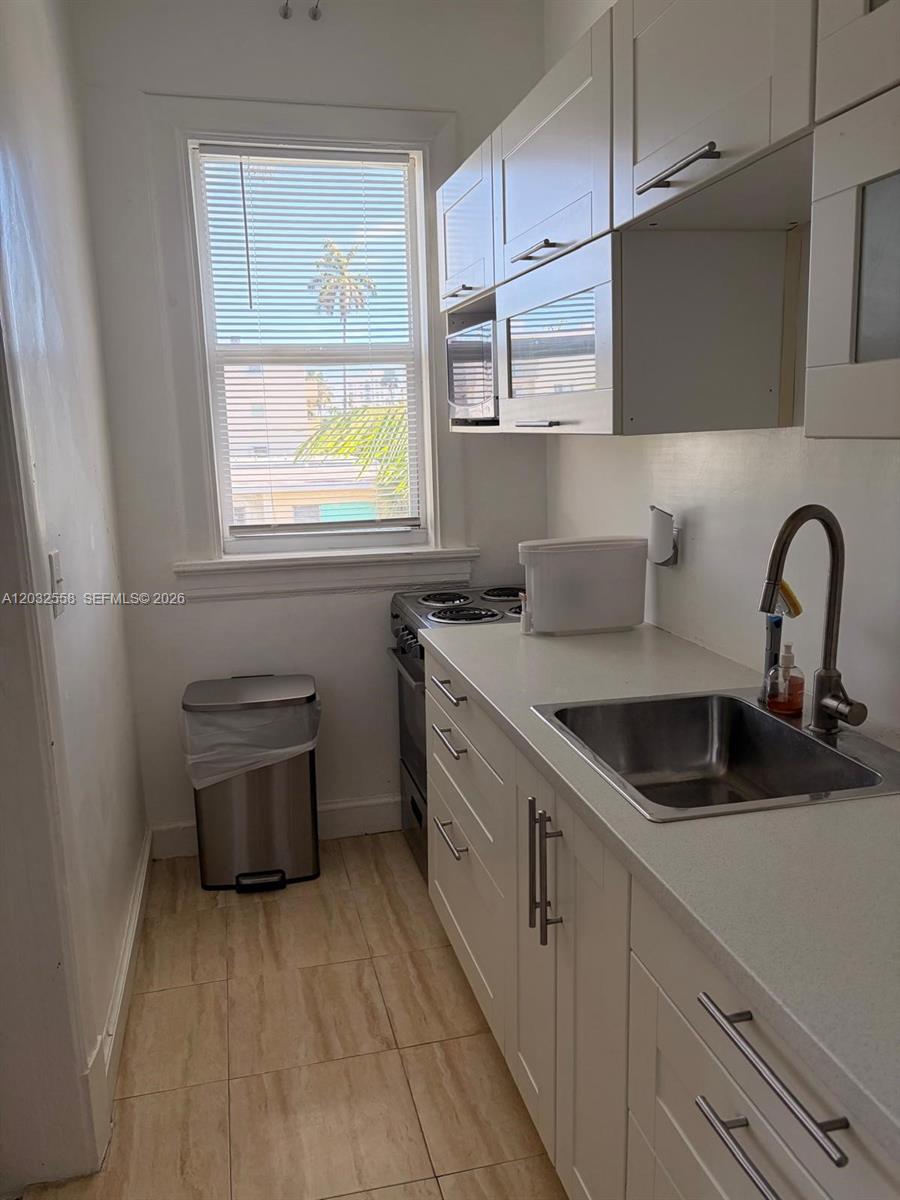 A small kitchen features white cabinets, a stainless steel sink, and a window with blinds — 900 16th St # 301, Miami Beach FL 33139, MIAMI BEACH, FL