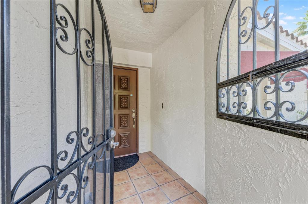 An entryway features a tiled floor, a brown wooden door, and decorative black metal gates — 6101 34TH STREET W UNIT 11G, BRADENTON, FL
