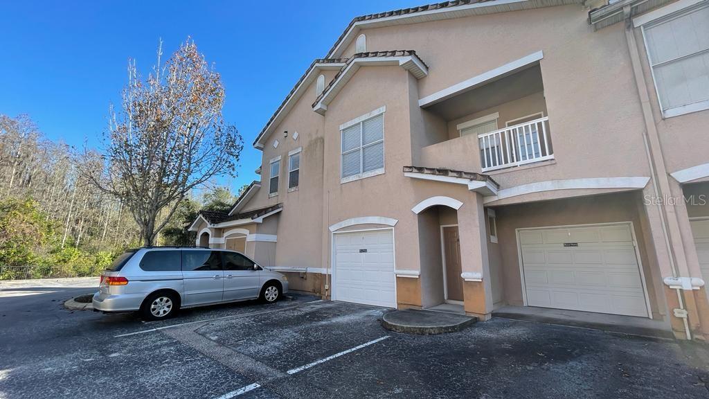 A two-story tan stucco townhouse with two garage doors and a second-floor balcony — 10539 VILLA VIEW CIRCLE UNIT 10539, TAMPA, FL