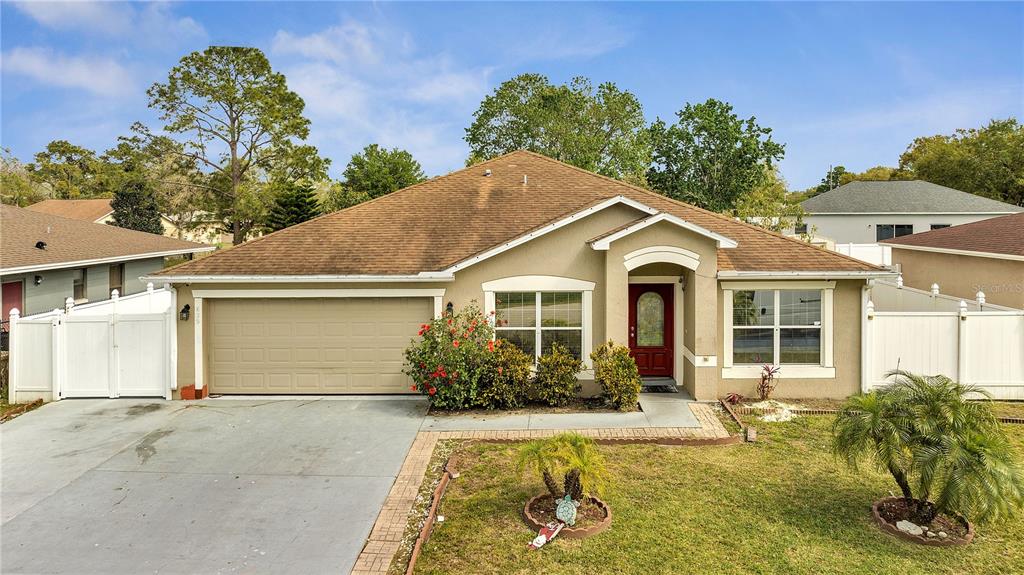 A single-story house with a tan stucco exterior, brown roof, and a two-car garage — 639 MESILLA DRIVE, KISSIMMEE, FL
