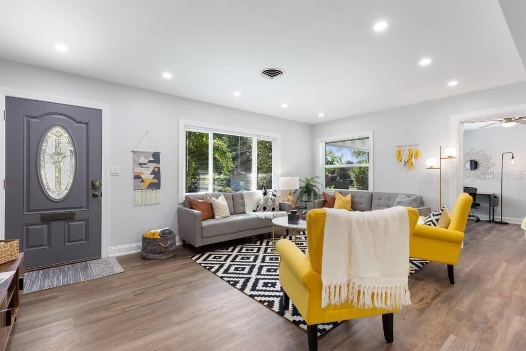 A living room features gray sofas, yellow armchairs, a patterned rug, and a gray door — 2120 1ST STREET N, ST PETERSBURG, FL