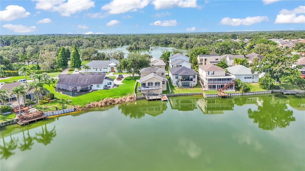 An aerial view shows several waterfront houses with docks along a lake in a neighborhood — 601 PENINSULAR DRIVE, LAKELAND, FL