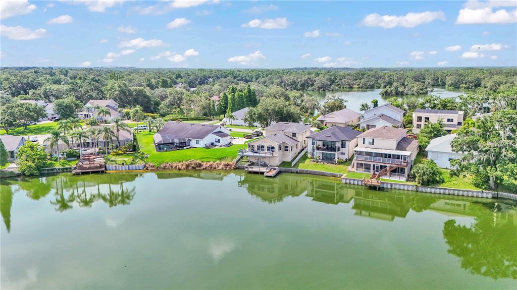 An aerial view of waterfront houses with private docks along a green lake — 601 PENINSULAR DRIVE, LAKELAND, FL