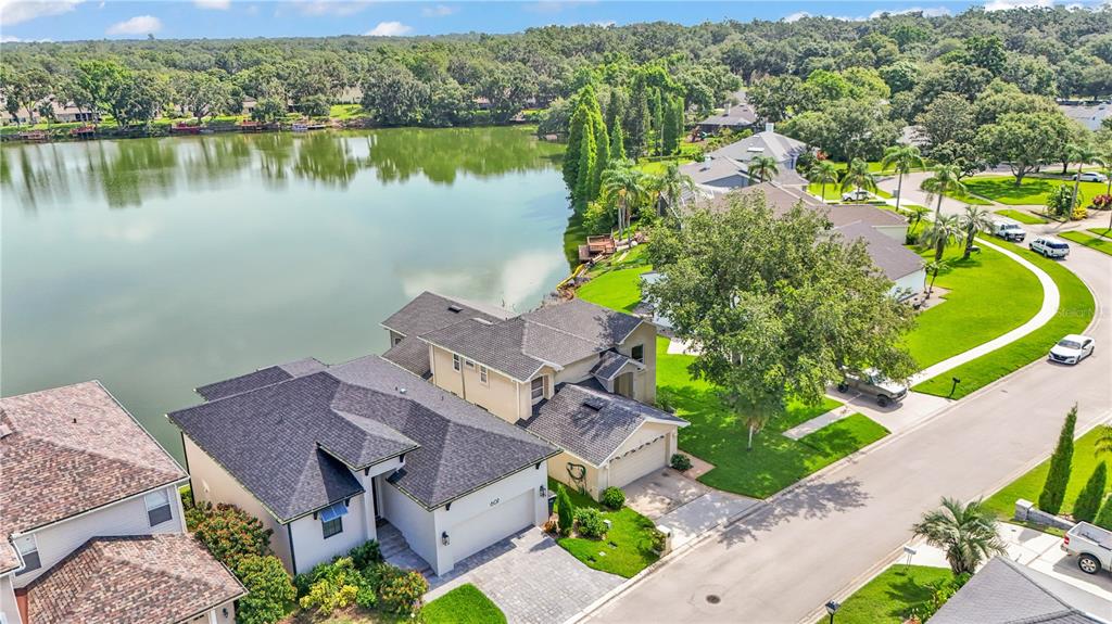 An aerial view shows a suburban house with a dark roof beside a large lake — 601 PENINSULAR DRIVE, LAKELAND, FL