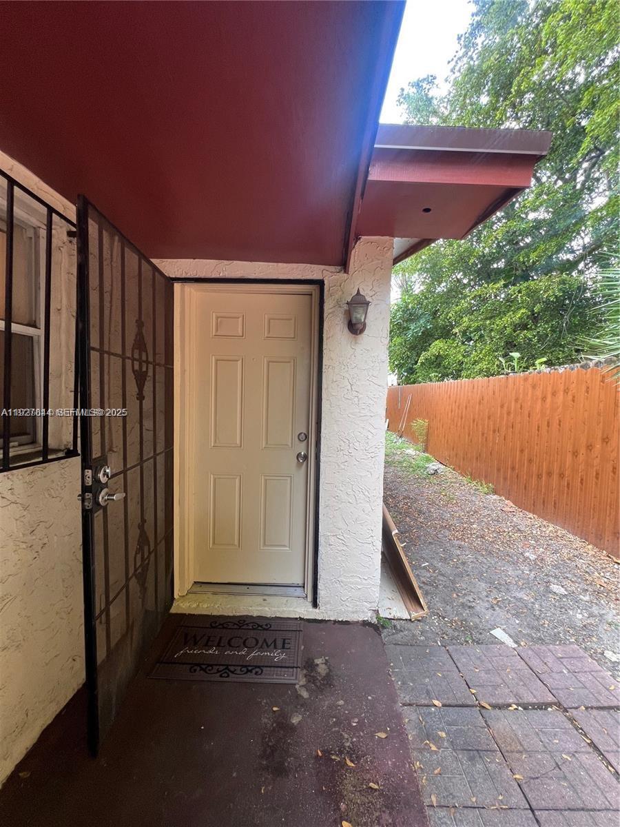 A beige exterior door with a security screen door opens onto a small concrete patio — 1581 NE 117 ST, Miami FL 33161, MIAMI, FL