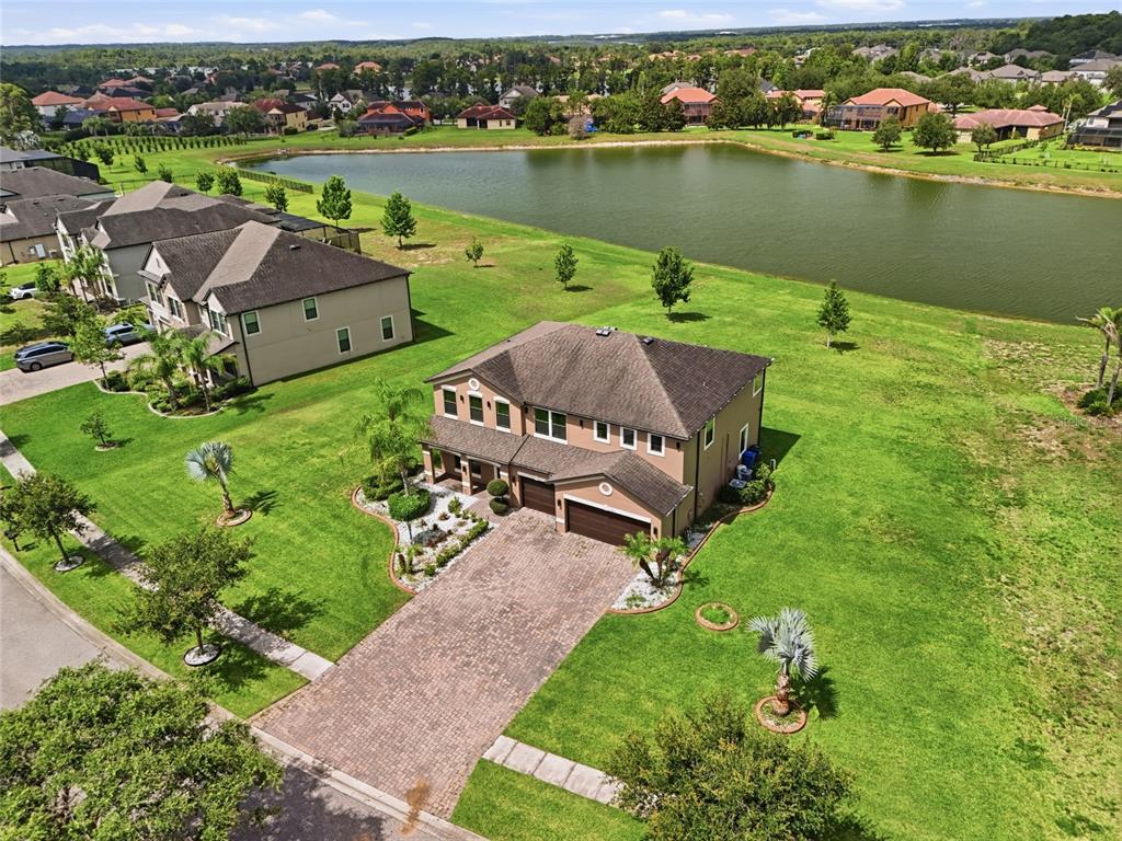 An aerial view shows a two-story house with a brick driveway near a lake — 9410 LISBON STREET, SEFFNER, FL