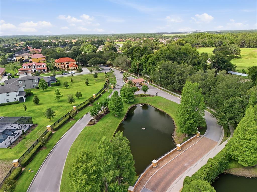 An aerial view shows a gated residential community entrance with a pond and landscaped grounds — 9410 LISBON STREET, SEFFNER, FL