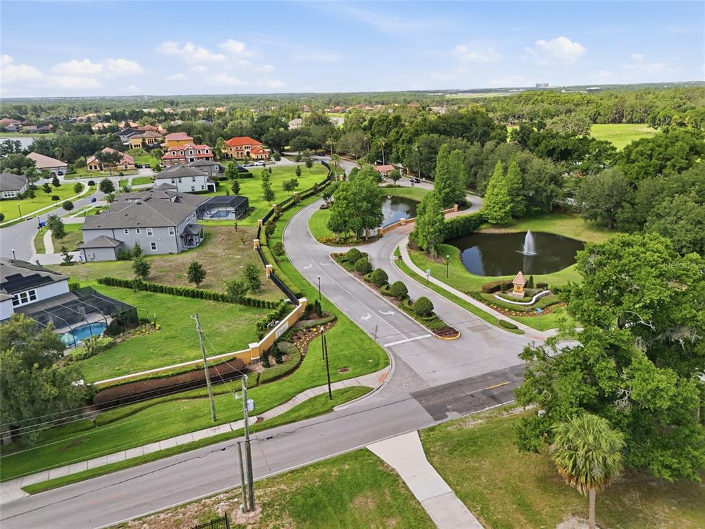 An aerial view shows a residential neighborhood entrance with a fountain, pond, and paved roads — 9410 LISBON STREET, SEFFNER, FL