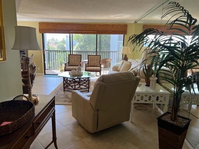 A living room features a beige recliner, a glass-topped coffee table, and a balcony view — 1605 S Us Highway 1 # A301, Jupiter FL 33477, JUPITER, FL